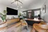 Modern office space featuring contemporary decor, sleek desk with leather chair, stylish wooden sideboard, and chic wall art, complemented by natural light from large windows.