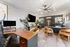 Modern office space with stylish wooden desks, ergonomic chairs, contemporary lighting, and vibrant indoor plants.