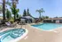 Inviting outdoor pool area featuring a sparkling swimming pool, relaxing loungers, and shaded seating amid lush greenery.