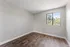 Bright and spacious bedroom with elegant wood flooring and a large window offering serene outdoor views.