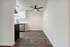 Modern kitchen and dining area with sleek white cabinets, stylish ceiling fan, and elegant wood flooring.