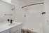 Modern bathroom with sleek black fixtures, a pristine white vanity, and a spacious shower tub combo in a stylish apartment.