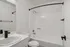 Modern bathroom with sleek black fixtures, elegant white countertop, and a spacious bathtub with a curved shower rod.