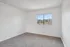 Bright and airy bedroom with soft carpet flooring and a large window offering a stunning hillside view.