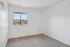 Bright bedroom with large window showcasing scenic hill views, fresh white walls, and cozy carpet, perfect for relaxation.
