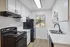 Contemporary kitchen with sleek white cabinets, modern black appliances, and a scenic window view.