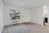 Bright living space with plush carpet, large window with scenic view, and access to modern kitchen.