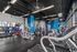 Modern fitness center with state-of-the-art equipment, vibrant blue accents, and panoramic windows offering city views.