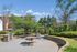 Charming outdoor grilling area with picnic tables set amidst lush greenery and views of a modern apartment complex.
