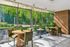 Bright and modern dining area with large windows showcasing lush greenery, featuring elegant wooden tables and comfortable seating.