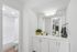 Elegant bathroom design with dual sinks, modern lighting, and a plant accent, leading to a bright and inviting shower area.