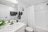 Bright, modern bathroom with sleek white vanity, elegant brass fixtures, and luxurious shower area.