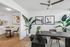 Chic modern dining area with sleek black table, stylish artwork, and lush indoor plants adjacent to a contemporary kitchen.