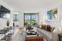 Elegant, modern living room with plush seating, large artwork, and a stunning view through floor-to-ceiling windows leading to a balcony.
