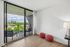 Bright apartment with floor-to-ceiling windows showcasing a scenic city view, private balcony, and cozy modern decor.