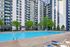 Luxurious apartment complex with a sparkling pool, surrounded by lush trees and modern buildings.
