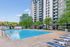 Luxurious apartment complex featuring a sparkling pool with sun loungers and vibrant greenery, perfect for relaxation.