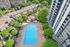Aerial view of a vibrant apartment complex featuring a large, inviting swimming pool surrounded by lush greenery and modern buildings.