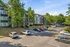 Charming apartment complex with lush greenery, ample parking, and well-maintained modern buildings under a clear blue sky.
