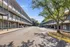 Inviting apartment complex with modern balconies, ample parking, and lush greenery under a clear blue sky.