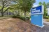 Inviting entrance to The Social Seminole apartments, surrounded by lush greenery and tall trees, highlighted by a bold blue sign.
