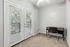 Bright and airy room with plush carpeting, featuring a cozy work desk by glass doors opening to a tranquil balcony view.