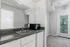 Chic apartment kitchen with modern countertop, sink, microwave, mini fridge, and bright natural light.