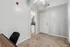 Cozy apartment corner with plush carpet, modern ceiling fan, and sleek white door leading to a compact kitchen area.