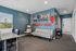 Contemporary apartment lounge with chic hanging chair, sleek gray sofa, and motivational wall art in vibrant blue hues.