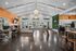 Modern and inviting communal space with sleek design, featuring a spacious kitchen and work area under a vaulted ceiling with stylish lighting.