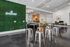 Chic communal space featuring modern high-top tables and stools, vibrant green accent wall, and a cozy lounge area.