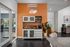 Inviting apartment common area with a chic caf&eacute; station, vibrant orange accent wall, and modern decor.