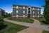 Charming three-story apartment building with a beautiful brick and grey siding exterior, surrounded by lush green lawns and winding sidewalks.