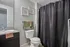 Elegant bathroom with modern fixtures, granite countertop, and stylish decor, featuring floral wall art and a textured shower curtain.