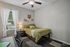 Cozy bedroom with inviting green bedding, modern desk, and charming decor, enhanced by natural light filtering through elegant curtains.