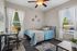 Cozy bedroom with a stylish blue comforter, elegant wall decor, and a bright workspace by the window.