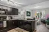 Modern kitchen with sleek black cabinetry, granite countertops, and cozy living area in a bright, welcoming apartment with natural light.