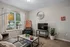 Contemporary living room with elegant decor, featuring a sleek leather sofa, modern TV setup, and large windows allowing abundant natural light.