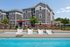 Charming apartment building with a refreshing poolside area, stylish loungers, and vibrant umbrellas, perfect for relaxation and leisure.