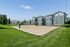 Charming apartment complex featuring elegant architecture and a well-maintained sand volleyball court surrounded by lush greenery.