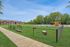 Expansive pet-friendly outdoor area featuring lush green lawn, agility obstacles, and cozy seating, perfect for relaxation and play.