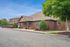 Charming brick leasing office with manicured landscaping under a clear blue sky.