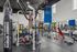Modern gym facility with a variety of equipment including a punching bag, colorful medicine balls, and weight machines under high ceilings and natural light.