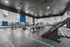 Spacious and well-equipped gym featuring modern cardio machines, weightlifting equipment, and a sleek Jacobs Ladder in an airy setting with large windows.