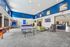 Spacious recreational room with modern decor featuring a table tennis setup, plush seating area, and vibrant blue accents ideal for gatherings and leisure.
