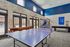Vibrant recreation room featuring a ping pong table, arcade basketball hoop, and pool table with poolside view.