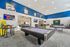 Vibrant recreational lounge featuring a modern billiards table, ping pong table, and cozy seating with stylish decor and bright lighting.