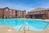 Inviting apartment complex featuring a luxurious outdoor pool and elegant brick architecture under clear blue skies.