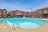 Inviting outdoor pool area surrounded by modern brick apartments and lush greenery, perfect for relaxation and leisure.