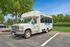 Inviting white shuttle bus parked in a tranquil setting with lush green trees, perfect for leisurely community rides at The Social Blue.